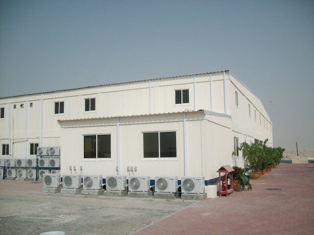 Multi-unit prefabricated industrial complex featuring climate-controlled modular housing and durable corrugated roofing for extreme Middle Eastern weather conditions.